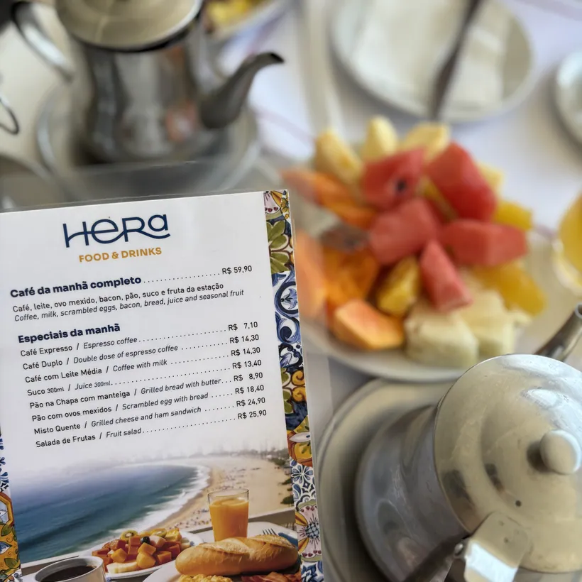 Hera's breakfast menu card on the table, next to a plate of fruit