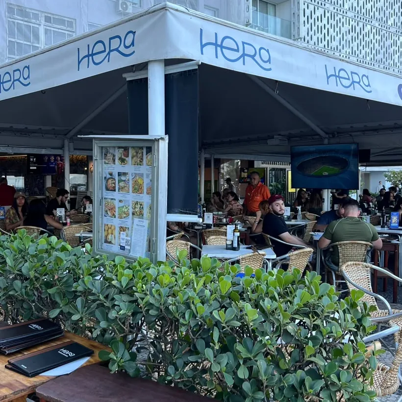 Hera Bar e Botequim's storefront with the blue awning on Avenida Atlântica